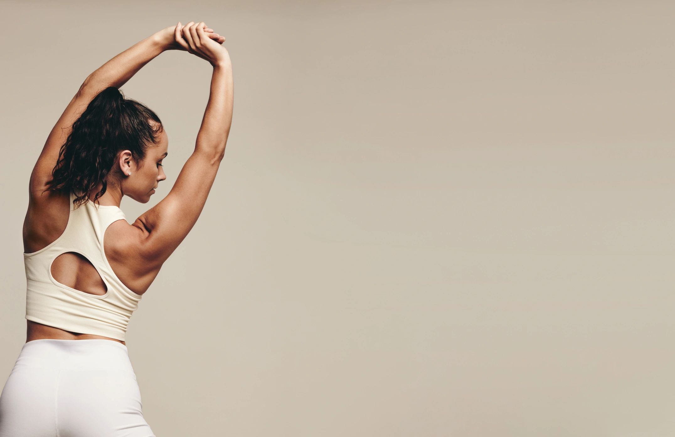 Athletic woman stretching in a neutral studio setting